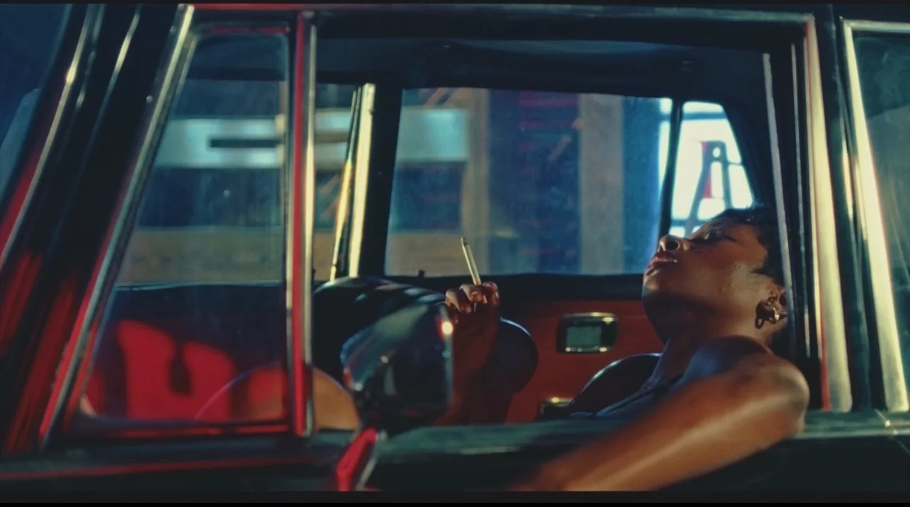 A woman reclining in the driver's seat of a colourfully lit car