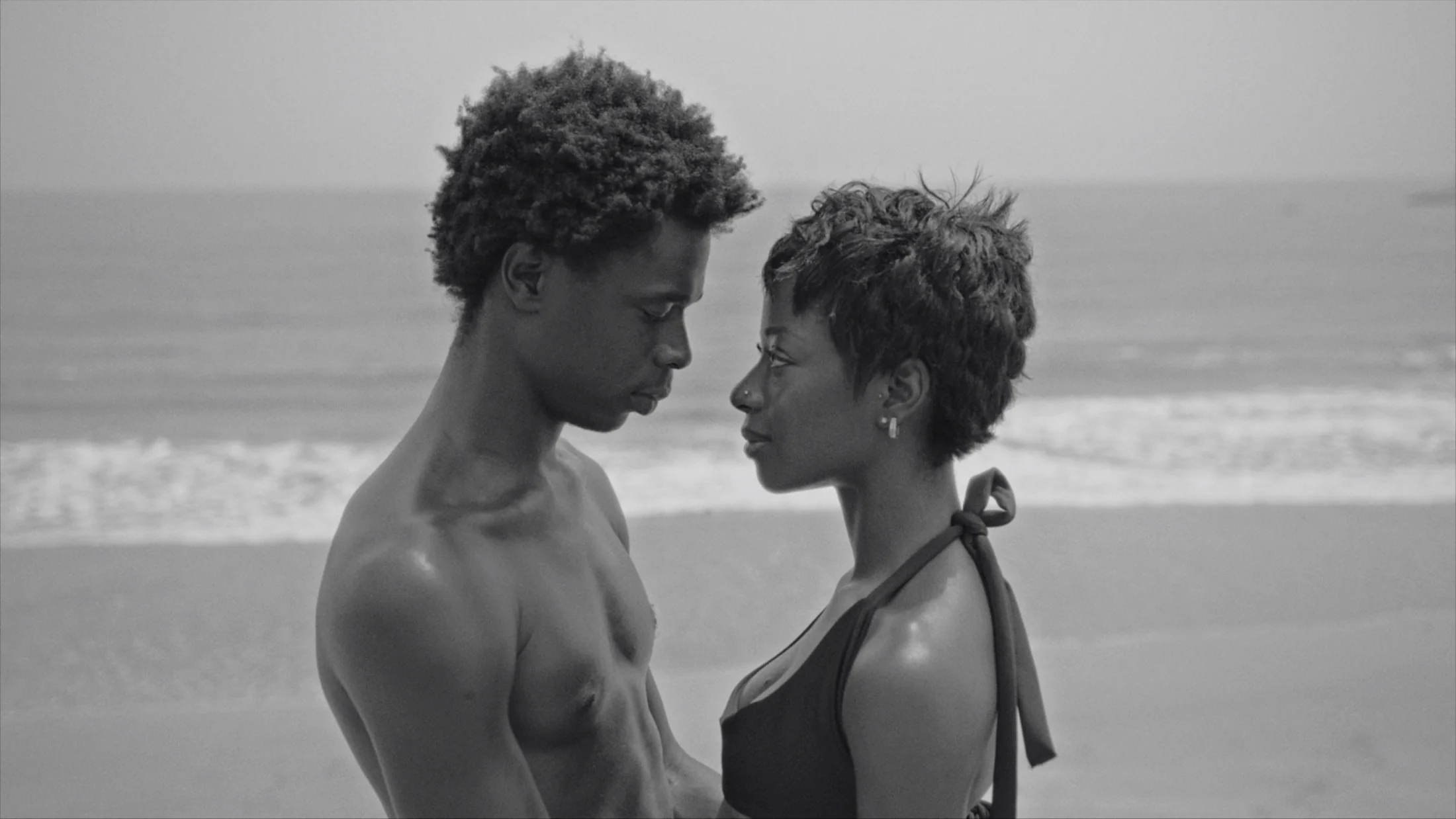 Two people standing face to face on a beach in black and white