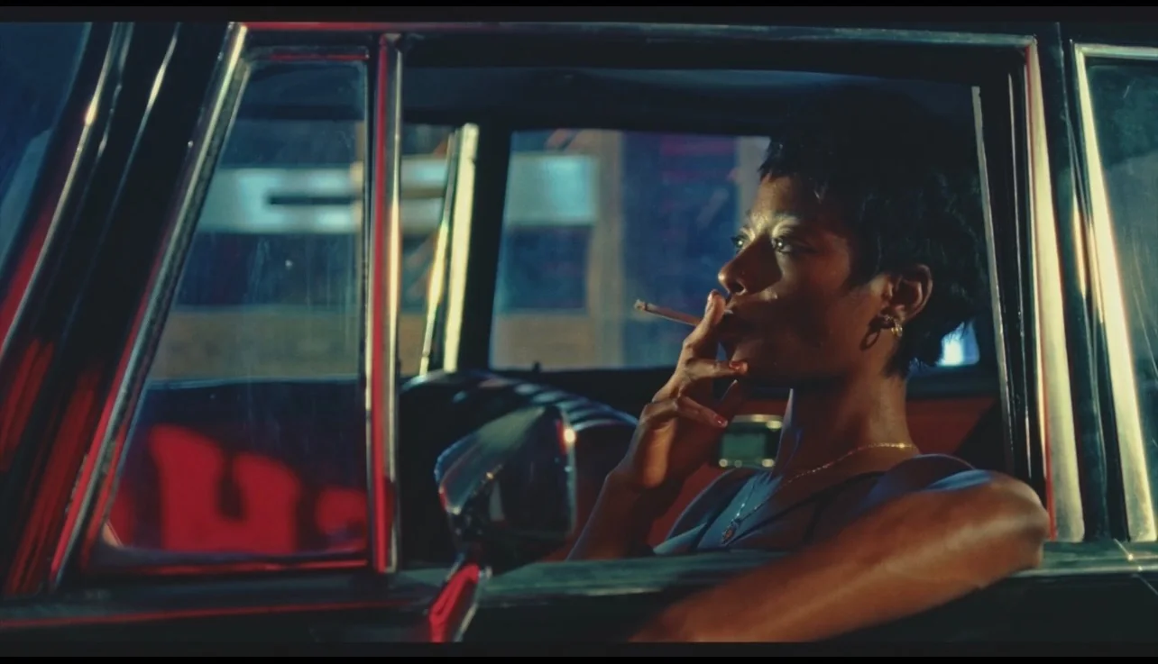 A woman smoking while seated inside a car at night